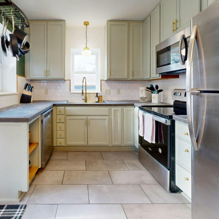 AppliancesModern kitchen with light gray cabinets, stainless steel appliances, and a central sink beneath a window. Warm lighting, neat and inviting space.